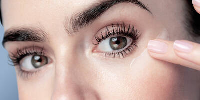 Woman applying eye cream around the eye contour area