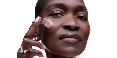 Mature woman with a deep skin tone applying Renergie Collagen Cream, part of the collagen-supporting routine