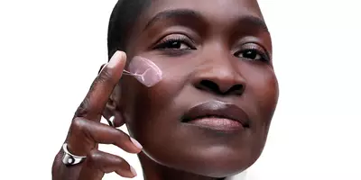 Mature woman with a deep skin tone applying Renergie Collagen Cream, part of the collagen-supporting routine