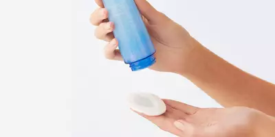 Woman showing how much makeup remover to dispense on a cotton pad
