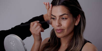 Model learning from makeup artist how to apply bronzer vs contour