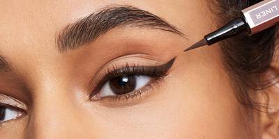 Woman applying brown liquid eyeliner in a winged eyeliner shape