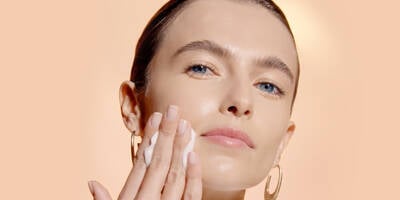 Woman showing how to use a face toner on skin with a cotton pad