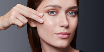 Woman applying foundation onto oily skin using fingertips