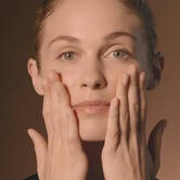Woman applying Absolue Overnight Serum to her skin using a pressing motion.